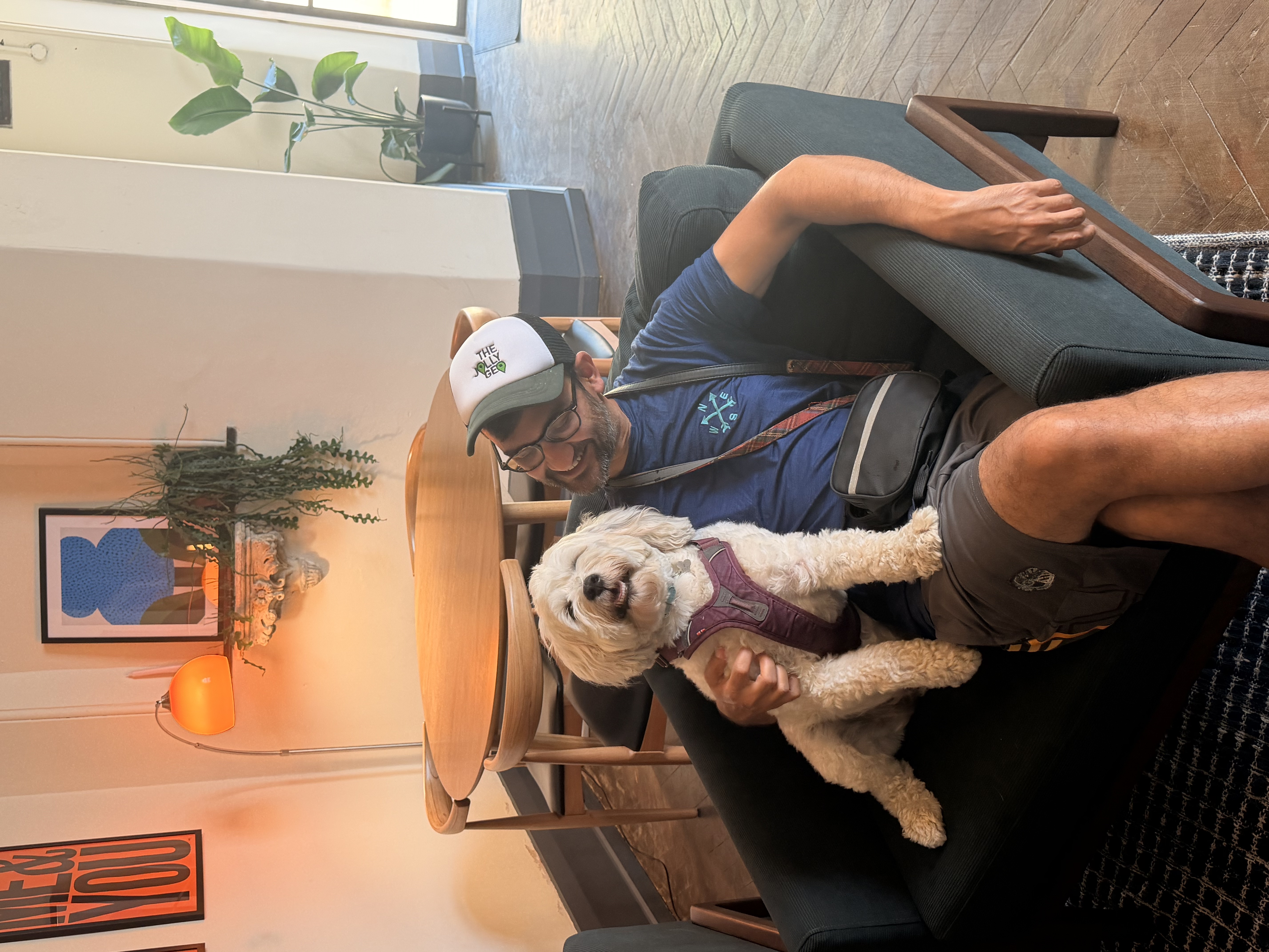 Owner relaxing in a cozy cafe armchair with their fluffy white dog
